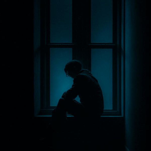 Person meditating peacefully by a window with soft light.